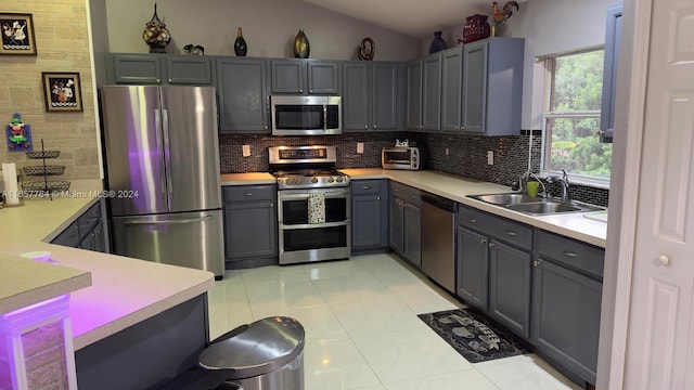 kitchen with vaulted ceiling, sink, gray cabinetry, appliances with stainless steel finishes, and light tile patterned flooring