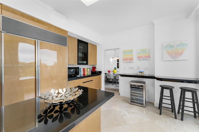 kitchen with wine cooler, ornamental molding, paneled built in fridge, and a kitchen bar