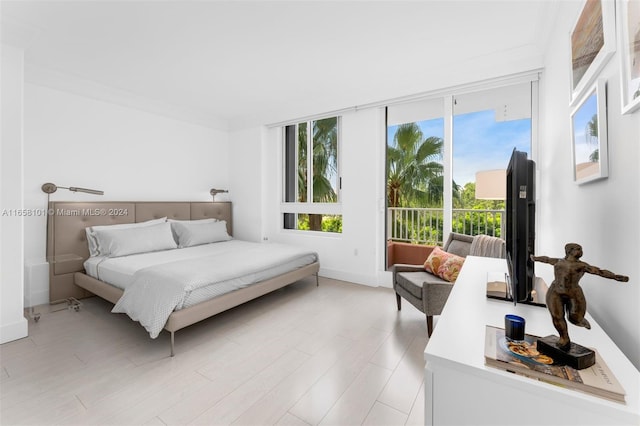 bedroom featuring ornamental molding, multiple windows, light hardwood / wood-style floors, and access to outside