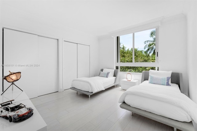 bedroom with light hardwood / wood-style flooring and two closets