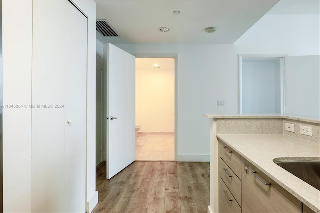 kitchen featuring light stone countertops, light wood-type flooring, sink, and light brown cabinets