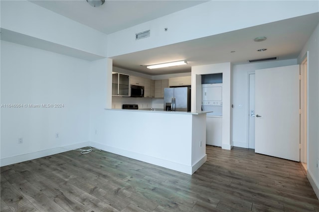 kitchen with appliances with stainless steel finishes, kitchen peninsula, and dark hardwood / wood-style flooring