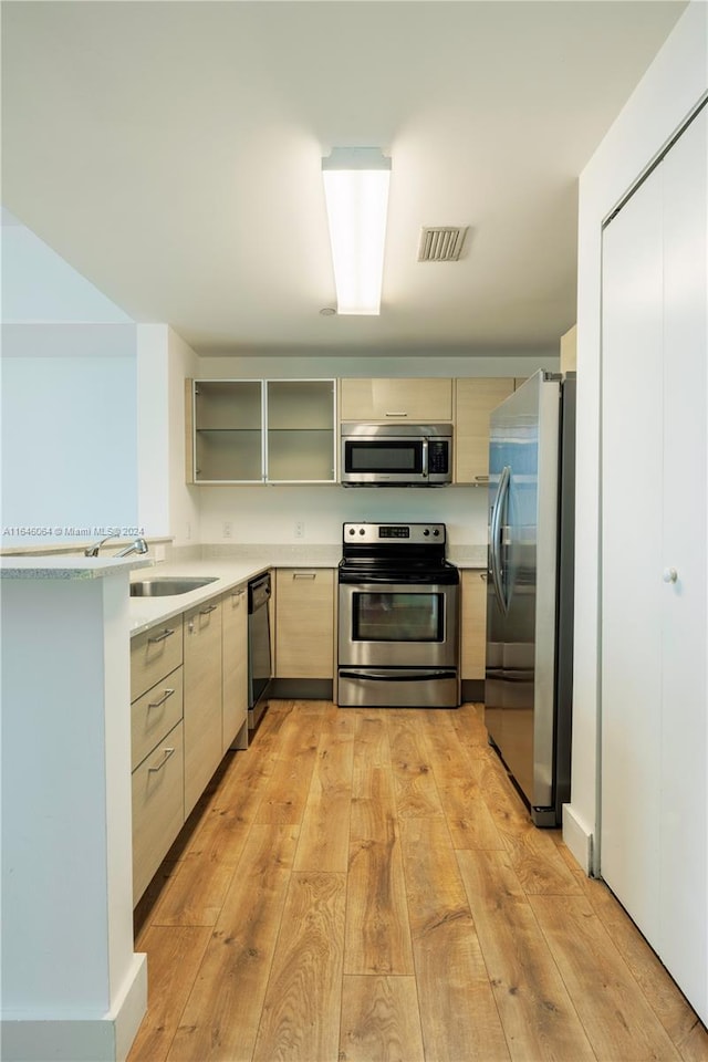 kitchen with light brown cabinets, light hardwood / wood-style flooring, stainless steel appliances, and sink