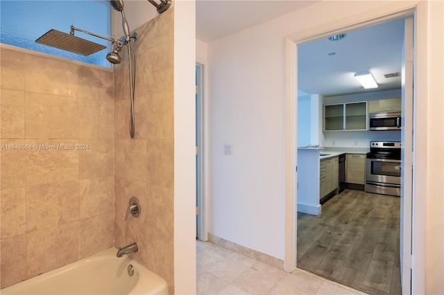 bathroom featuring wood-type flooring, tiled shower / bath, and vanity