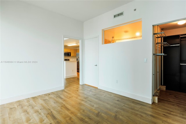 unfurnished bedroom with hardwood / wood-style floors, a walk in closet, and a closet