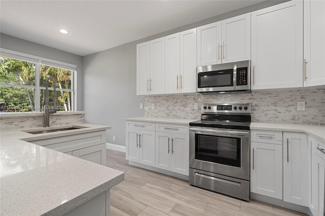 kitchen with white cabinets, appliances with stainless steel finishes, and decorative backsplash