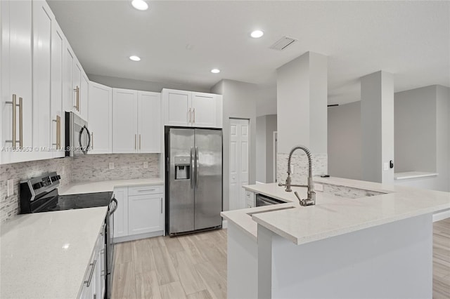 kitchen featuring white cabinets, backsplash, light stone countertops, stainless steel appliances, and light wood-type flooring