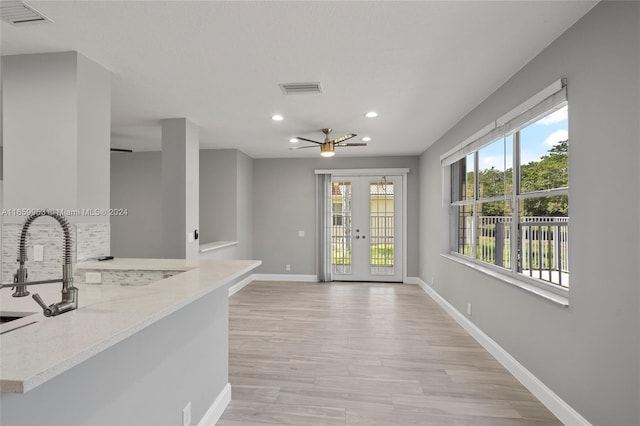 interior space with light wood-type flooring, light stone counters, french doors, and a wealth of natural light