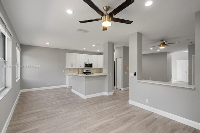 kitchen with ceiling fan, appliances with stainless steel finishes, kitchen peninsula, and white cabinetry