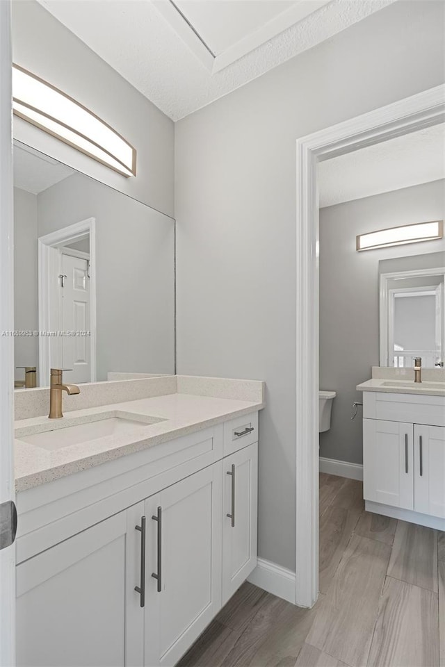 bathroom featuring wood-type flooring, vanity, and toilet