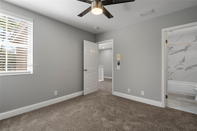 unfurnished bedroom with carpet floors, a textured ceiling, ensuite bath, and ceiling fan