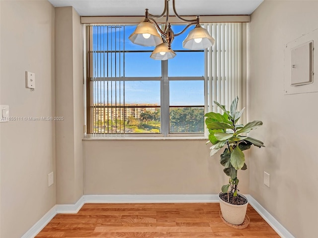 interior space featuring electric panel, light hardwood / wood-style flooring, and a notable chandelier