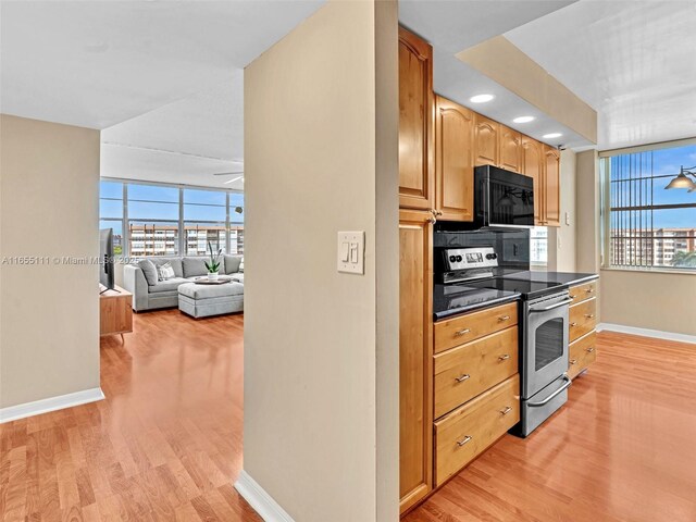 kitchen featuring stainless steel range with electric stovetop, ceiling fan, and light wood-type flooring