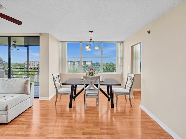 dining area with ceiling fan with notable chandelier, a textured ceiling, and light wood-type flooring