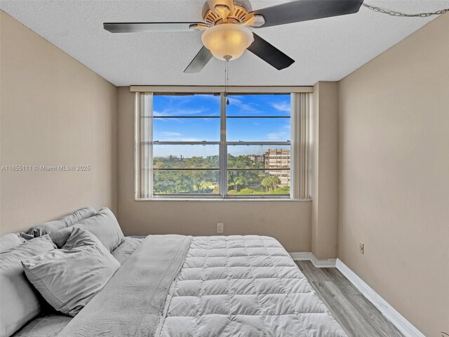 bedroom featuring a textured ceiling, ceiling fan, and light hardwood / wood-style flooring