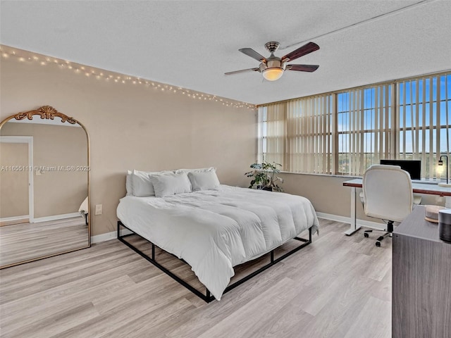 bedroom with light wood-type flooring, a textured ceiling, and ceiling fan