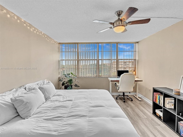 bedroom with ceiling fan, light hardwood / wood-style floors, and a textured ceiling