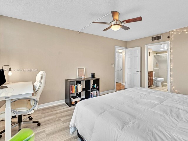 bedroom featuring light wood-type flooring, a textured ceiling, ceiling fan, and ensuite bath