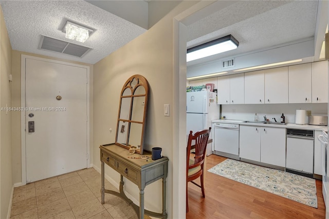 kitchen with white appliances, sink, a textured ceiling, white cabinetry, and light hardwood / wood-style flooring