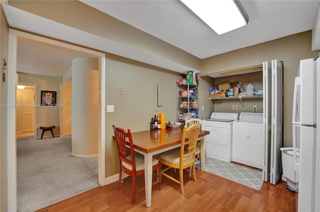 dining area with a textured ceiling, light hardwood / wood-style flooring, and washing machine and dryer