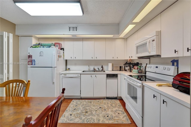 kitchen with light hardwood / wood-style floors, sink, white cabinetry, a textured ceiling, and white appliances