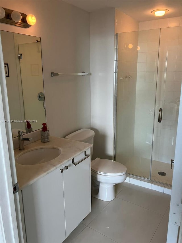 bathroom with tile patterned flooring, a shower with shower door, vanity, and toilet