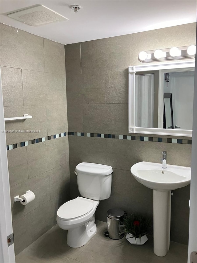 bathroom with tile walls, toilet, and tile patterned floors