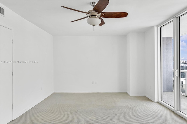 carpeted empty room featuring expansive windows and ceiling fan