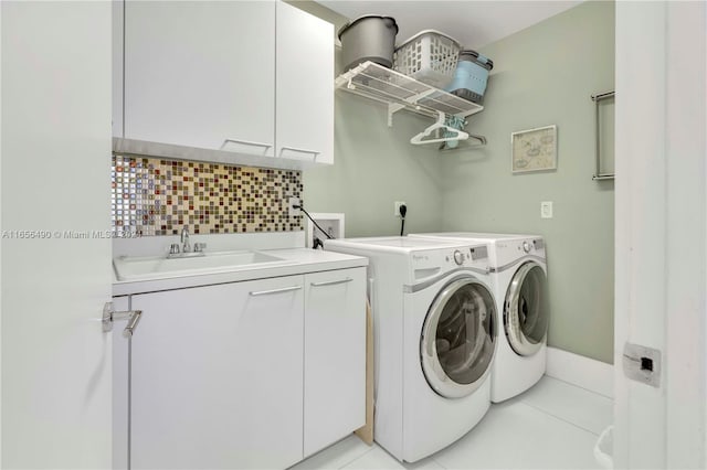 laundry room featuring light tile patterned floors, washing machine and clothes dryer, cabinets, and sink