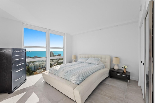 bedroom featuring a water view and expansive windows