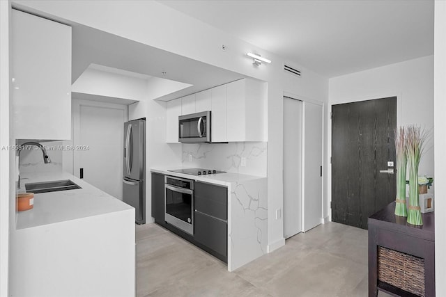 kitchen featuring tasteful backsplash, light stone counters, sink, appliances with stainless steel finishes, and white cabinets