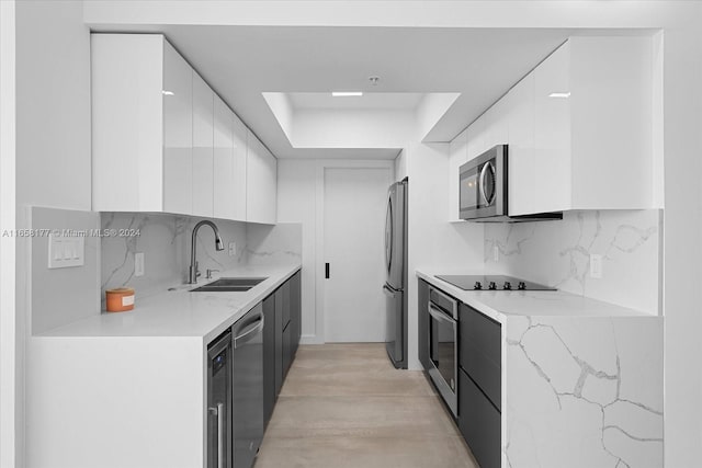 kitchen featuring white cabinets, appliances with stainless steel finishes, decorative backsplash, and sink