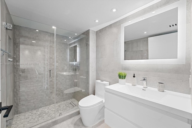 bathroom featuring a shower with door, vanity, toilet, and tile walls