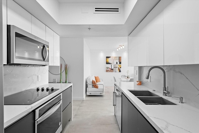 kitchen with tasteful backsplash, stainless steel appliances, sink, light stone countertops, and white cabinets