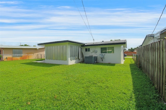 rear view of property featuring a yard and cooling unit