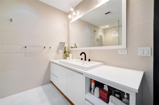 bathroom featuring a tile shower, vanity, and tile patterned floors