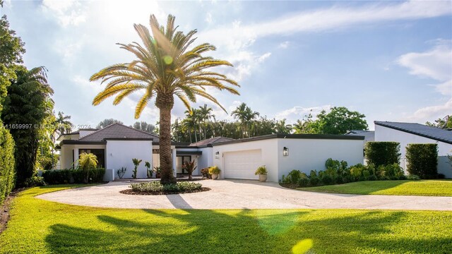 view of front of house with a front lawn, driveway, stucco siding, and a garage