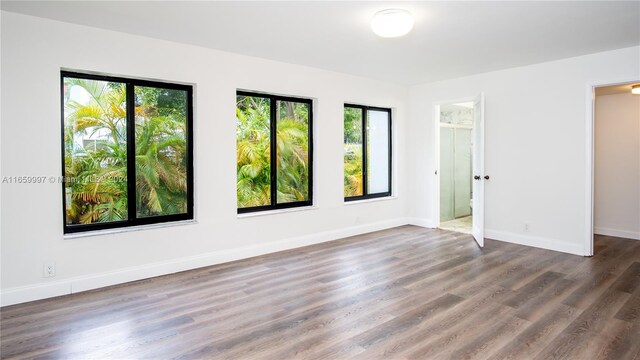spare room featuring baseboards and wood finished floors