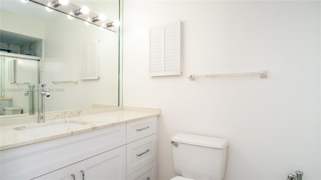 full bath with toilet, vanity, and a stall shower