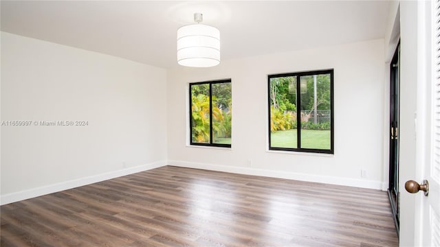 spare room with baseboards and wood finished floors