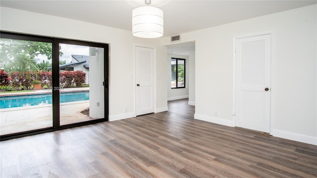 empty room with baseboards, visible vents, and wood finished floors