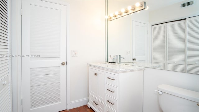 bathroom featuring toilet, vanity, a closet, and visible vents