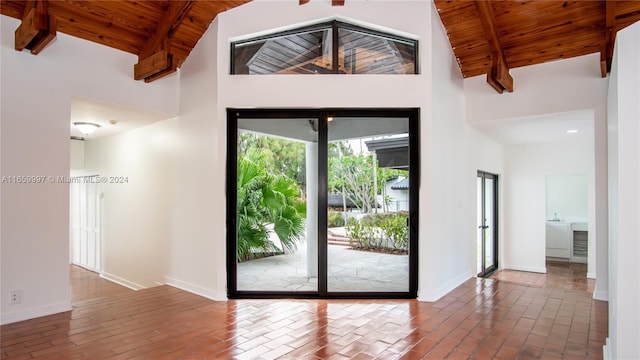 interior space featuring baseboards, high vaulted ceiling, wooden ceiling, and beam ceiling
