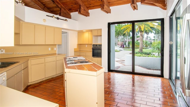 kitchen with oven, a healthy amount of sunlight, a center island, and vaulted ceiling with beams