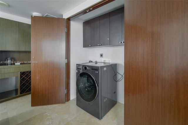 clothes washing area with washer / clothes dryer and cabinets