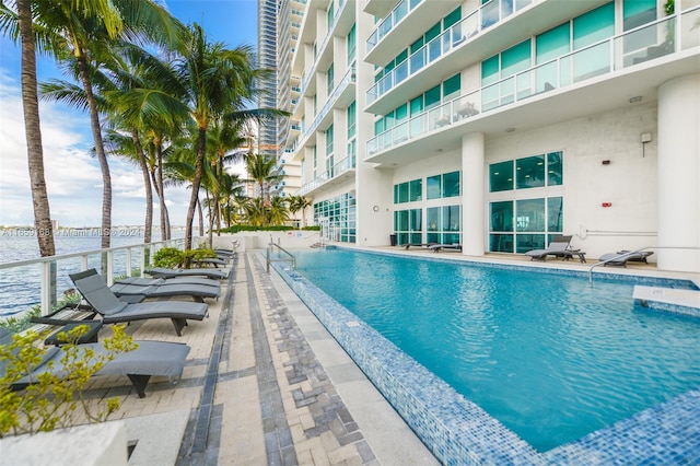 view of swimming pool with a water view and a patio area