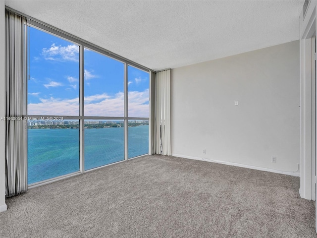 7601 E Treasure Dr Unit 2418, North Bay Village, FL 33141 - spare room featuring a water view, a textured ceiling, carpet floors, and expansive windows