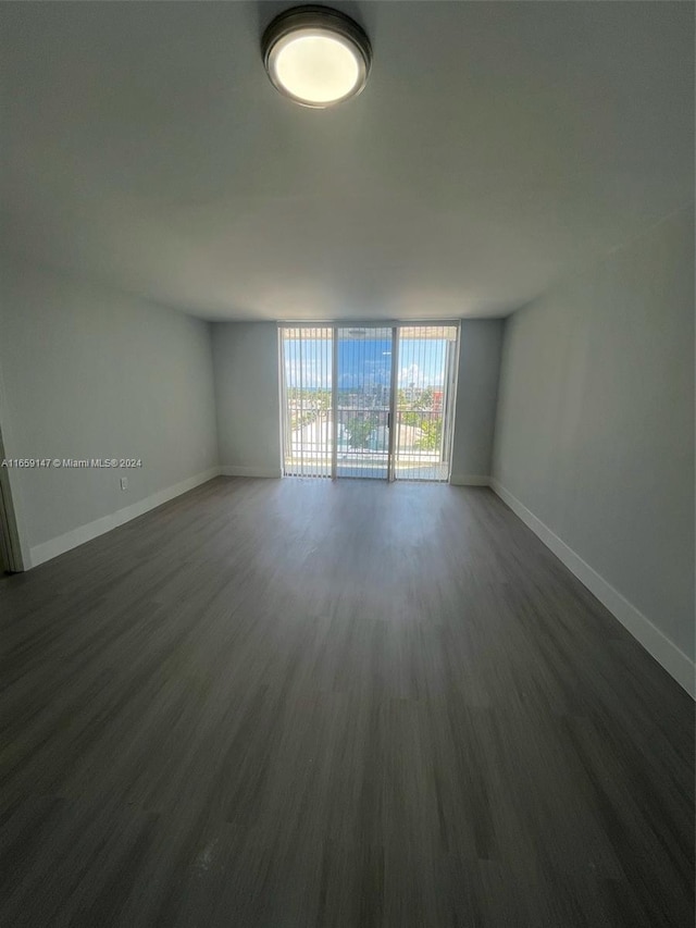 unfurnished room featuring expansive windows and dark hardwood / wood-style floors