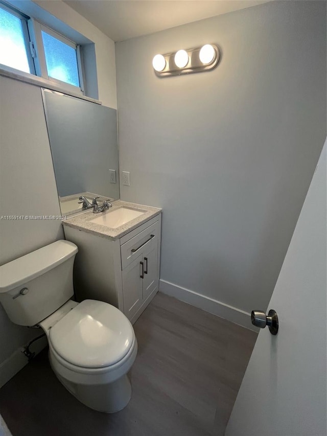 bathroom featuring wood-type flooring, vanity, and toilet