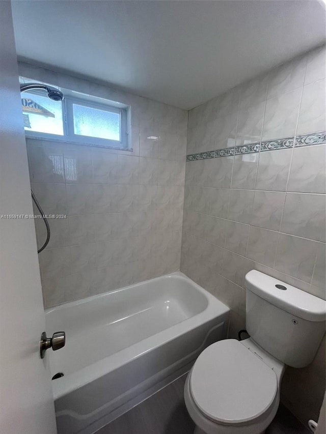 bathroom with tiled shower / bath, tile walls, and toilet